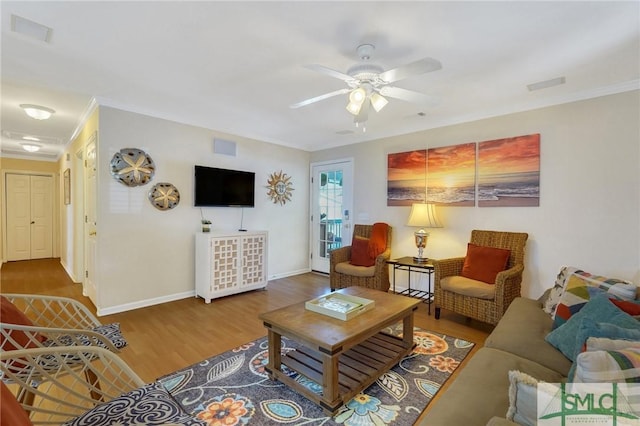 living area featuring ornamental molding, visible vents, baseboards, and wood finished floors