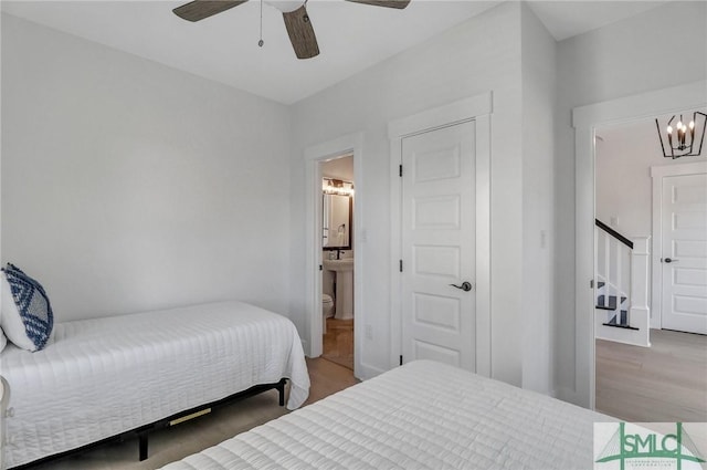 bedroom featuring ensuite bathroom, wood finished floors, and ceiling fan with notable chandelier