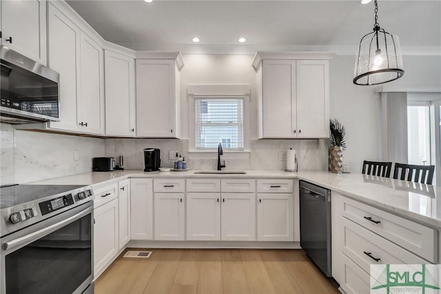 kitchen with white cabinets, appliances with stainless steel finishes, a sink, light countertops, and backsplash