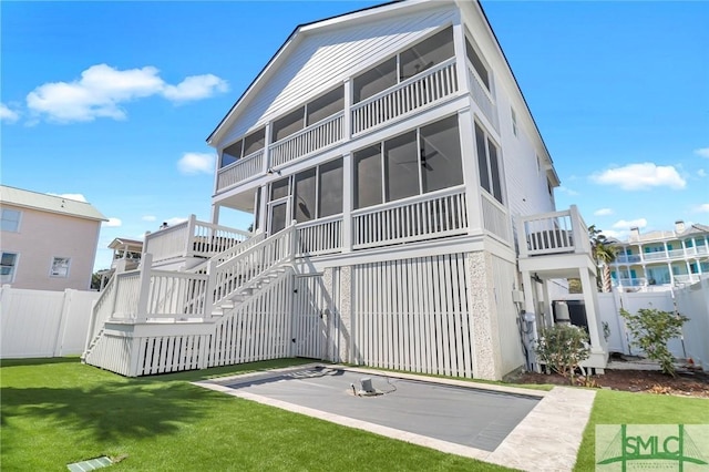 back of house featuring a yard, stairway, fence, and a sunroom