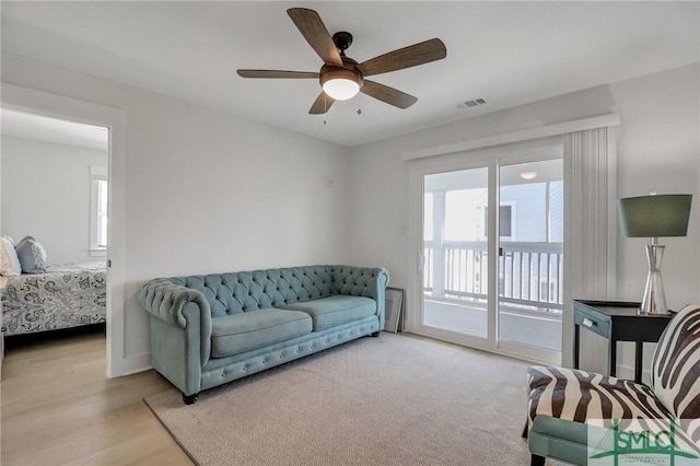 living room featuring light wood finished floors, ceiling fan, and visible vents