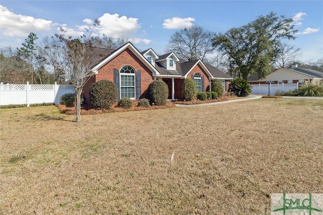 view of front facade with brick siding, a front lawn, a detached garage, and fence