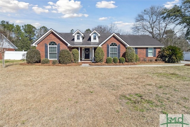 view of front of home featuring brick siding, a front lawn, and fence