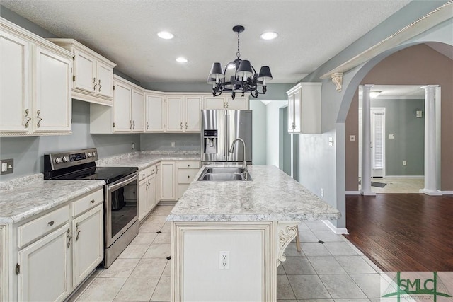 kitchen featuring light tile patterned floors, a kitchen island with sink, stainless steel appliances, a sink, and light countertops