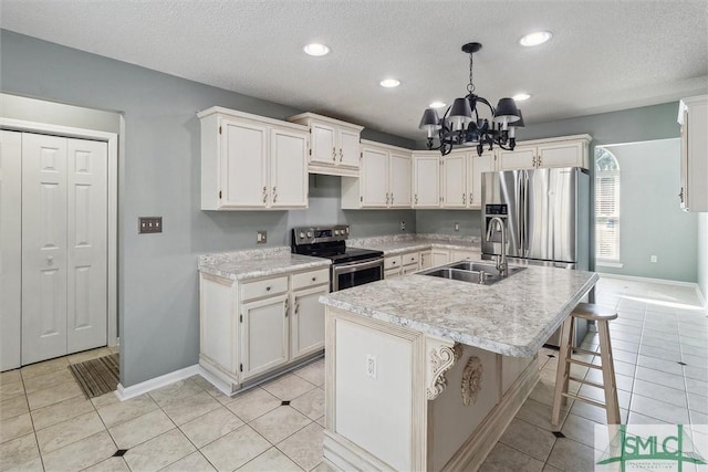 kitchen with appliances with stainless steel finishes, light countertops, a sink, and light tile patterned floors