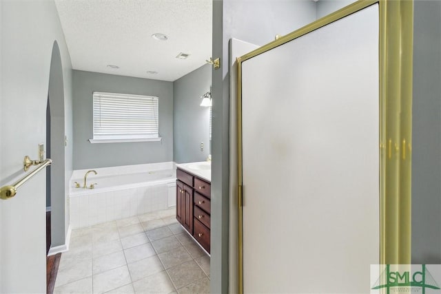 bathroom with a garden tub, visible vents, a textured ceiling, vanity, and tile patterned floors