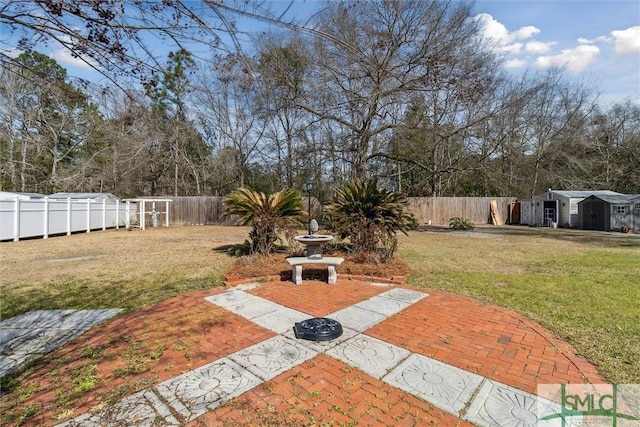 view of yard featuring a patio area, a fenced backyard, and an outbuilding