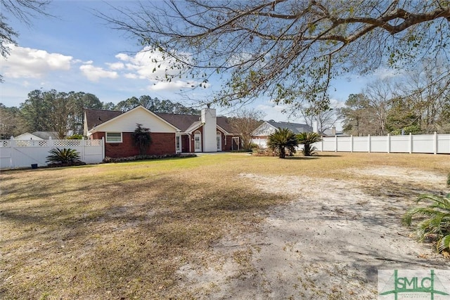 view of front of home with a chimney, fence, a front lawn, and brick siding