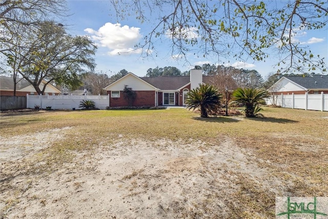 view of front facade with a chimney, fence, a front lawn, and brick siding