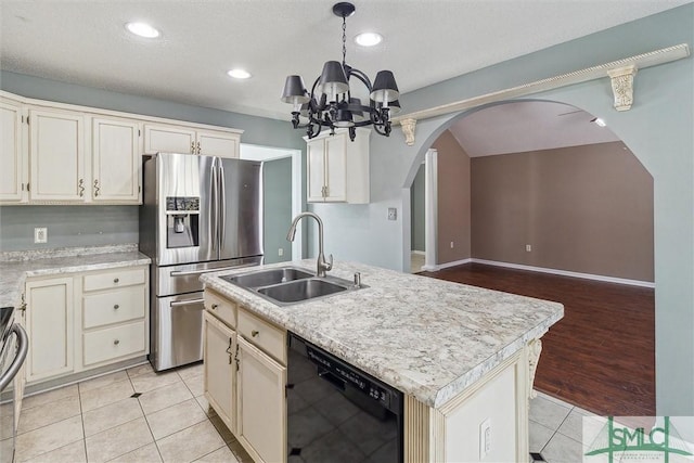 kitchen with light tile patterned floors, arched walkways, dishwasher, stainless steel fridge with ice dispenser, and a sink