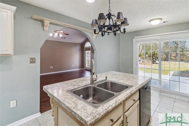 kitchen with arched walkways, dishwashing machine, a sink, and light countertops