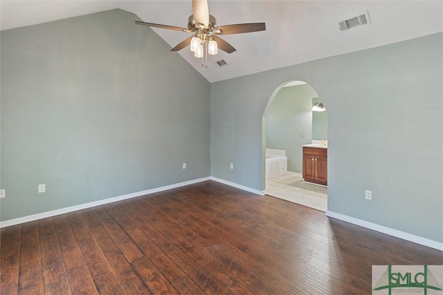 empty room featuring arched walkways, visible vents, ceiling fan, and hardwood / wood-style flooring