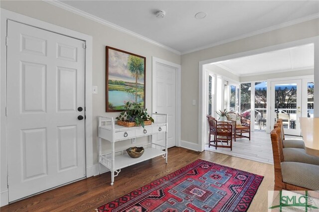 foyer entrance featuring ornamental molding, wood finished floors, and baseboards