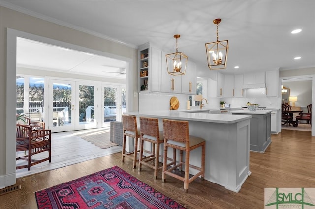 kitchen with light countertops, a peninsula, light wood-style flooring, and crown molding