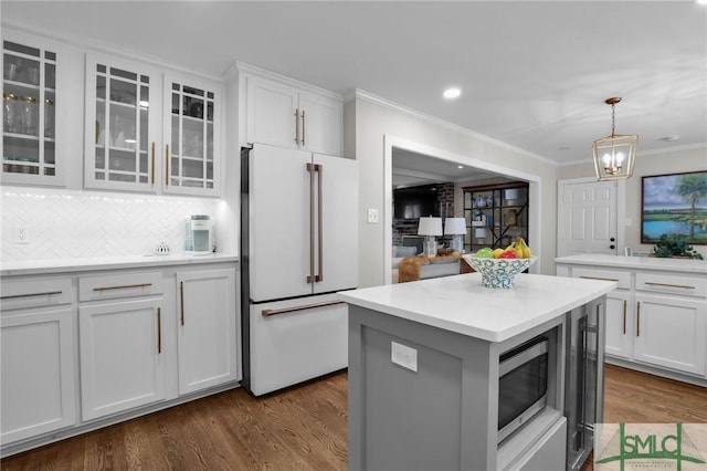 kitchen with white cabinets, stainless steel microwave, dark wood-type flooring, a center island, and freestanding refrigerator