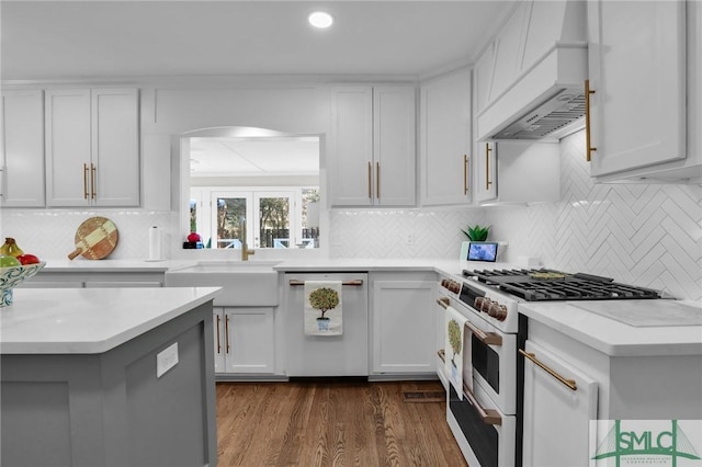 kitchen with white range with gas stovetop, dark wood-type flooring, a sink, dishwasher, and custom range hood