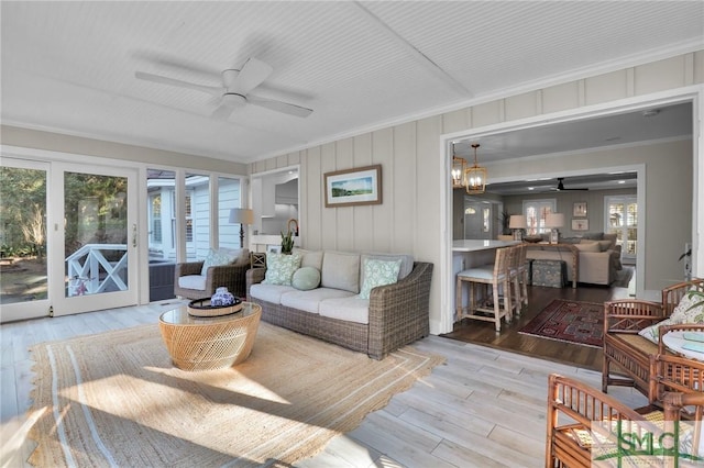 living area featuring ceiling fan, ornamental molding, and wood finished floors