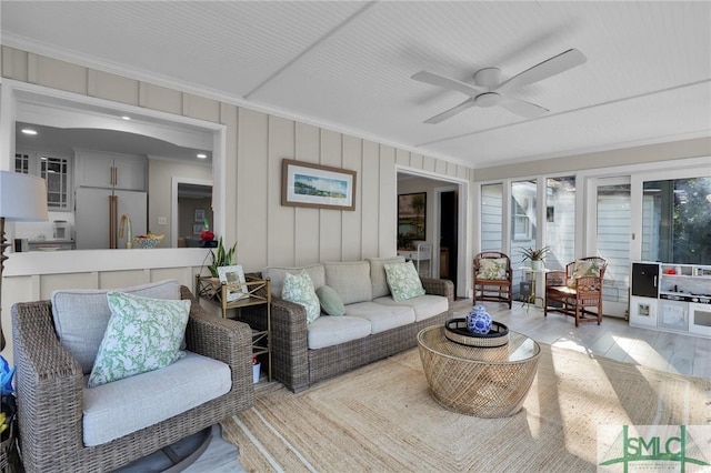 living area with ceiling fan, wood finished floors, and crown molding