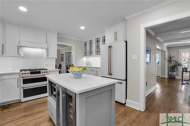 kitchen with wood finished floors, high quality appliances, white cabinets, glass insert cabinets, and crown molding