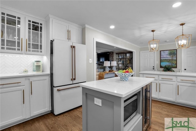 kitchen featuring white cabinets, a kitchen island, stainless steel microwave, dark wood-style flooring, and freestanding refrigerator