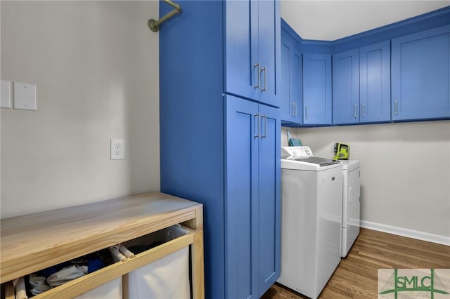 clothes washing area with cabinet space, baseboards, wood finished floors, and independent washer and dryer