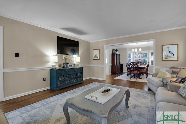 living area with a notable chandelier, ornamental molding, wood finished floors, and baseboards