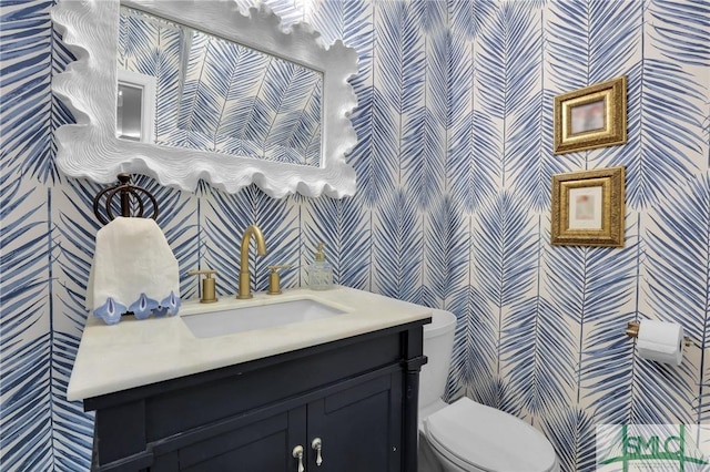 bathroom featuring vanity, toilet, and wallpapered walls