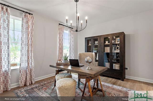 office space with a chandelier, wood finished floors, and baseboards