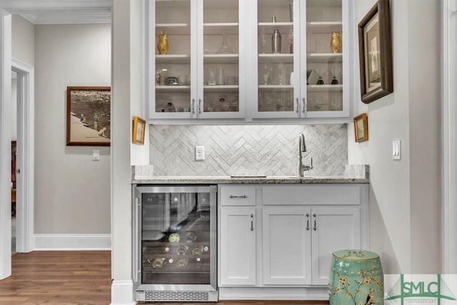 bar with dark wood-type flooring, wine cooler, backsplash, and a sink