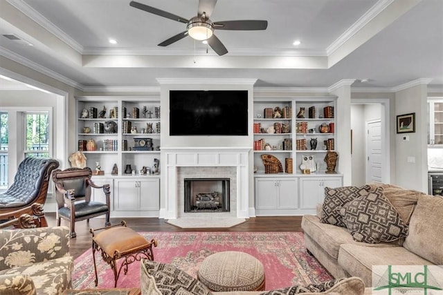 living room with a fireplace, a raised ceiling, ornamental molding, ceiling fan, and wood finished floors