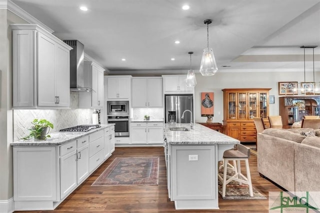 kitchen featuring stainless steel appliances, dark wood-style flooring, a sink, open floor plan, and wall chimney range hood