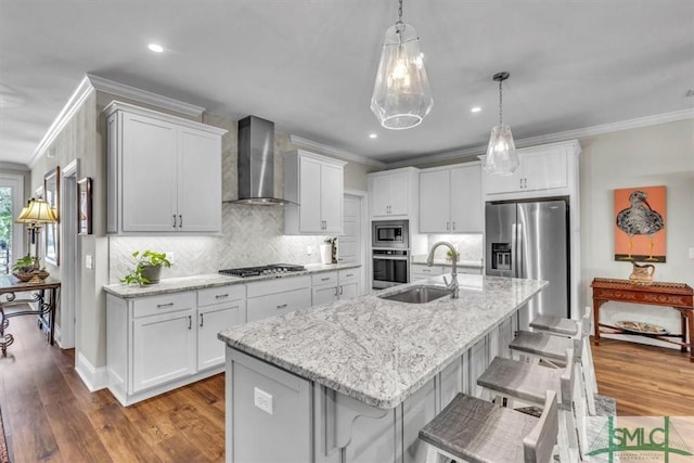 kitchen with wall chimney exhaust hood, ornamental molding, a sink, and stainless steel appliances