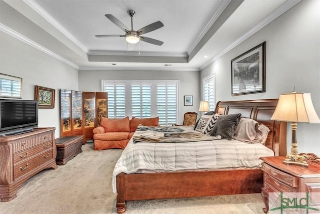 carpeted bedroom with ornamental molding, a raised ceiling, and a ceiling fan