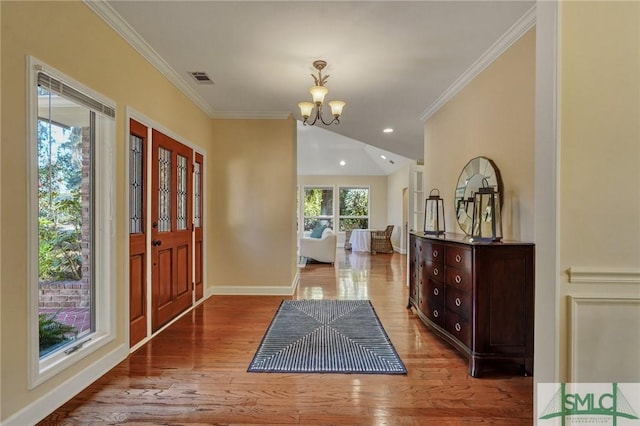 foyer entrance featuring ornamental molding, baseboards, an inviting chandelier, and wood finished floors