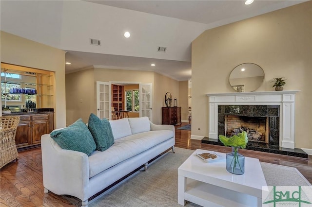 living room with plenty of natural light, visible vents, wood finished floors, a fireplace, and high vaulted ceiling