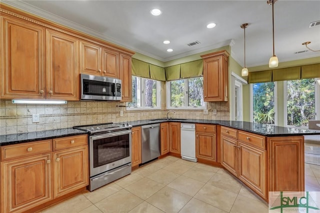 kitchen with dark stone counters, a peninsula, appliances with stainless steel finishes, and brown cabinets