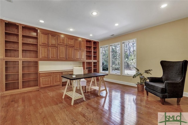 office area with light wood-type flooring, baseboards, ornamental molding, and built in study area