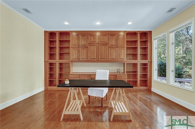 unfurnished office featuring baseboards, visible vents, light wood-style flooring, and ornamental molding