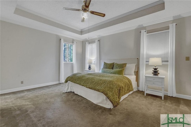 carpeted bedroom featuring a textured ceiling, a ceiling fan, baseboards, a raised ceiling, and crown molding