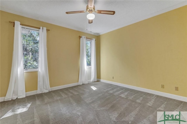 unfurnished room featuring carpet, baseboards, ceiling fan, and crown molding