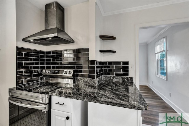 kitchen featuring ornamental molding, wall chimney range hood, white cabinets, and stainless steel range with electric cooktop