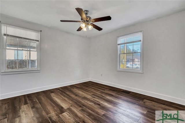 spare room featuring dark wood-type flooring, a ceiling fan, visible vents, and baseboards