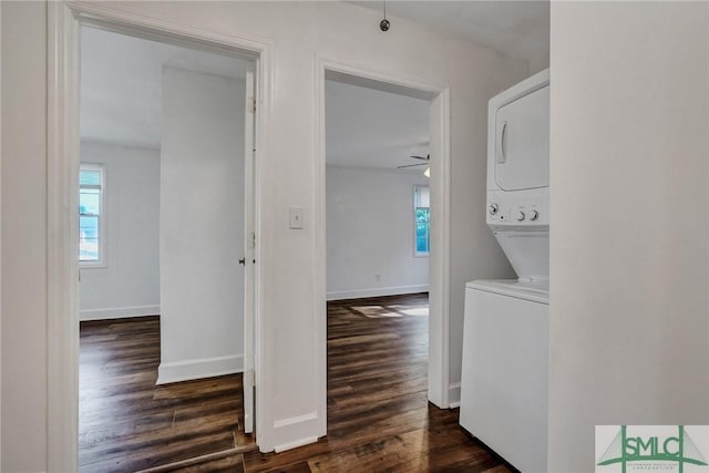 laundry room with ceiling fan, laundry area, dark wood-style flooring, stacked washer / dryer, and baseboards