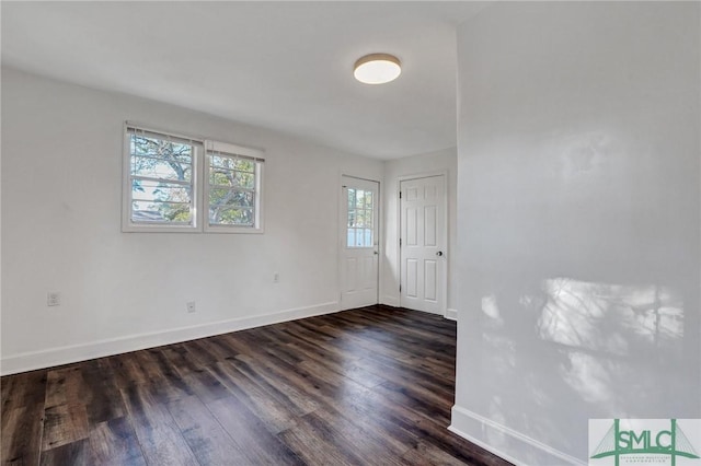 unfurnished room with dark wood finished floors and baseboards