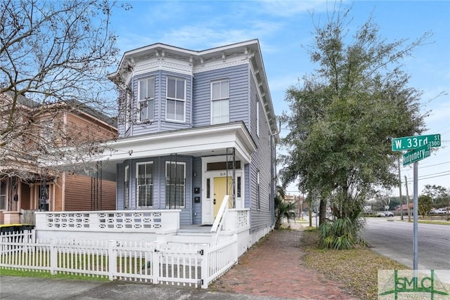 italianate-style house with a fenced front yard and a porch