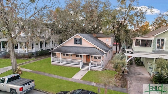 view of front of home featuring covered porch, a shingled roof, and a front yard