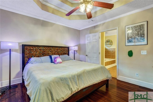 bedroom with baseboards, visible vents, wood finished floors, a tray ceiling, and crown molding