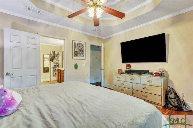 bedroom featuring visible vents, ceiling fan, ornamental molding, wood finished floors, and a tray ceiling