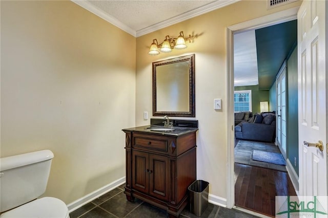 bathroom with toilet, ornamental molding, vanity, tile patterned flooring, and baseboards