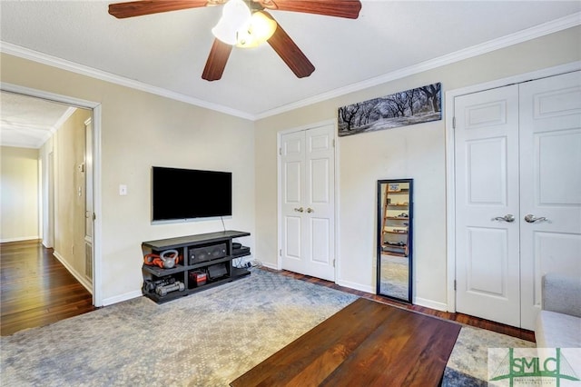 living room with a ceiling fan, crown molding, baseboards, and wood finished floors